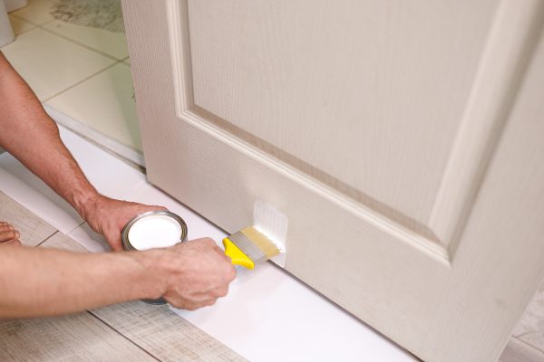 In her hands is a paintbrush that paints the door white. Repair staining the doors with paint. In her hands is a paintbrush that paints the door white. Repair staining the doors with paint.