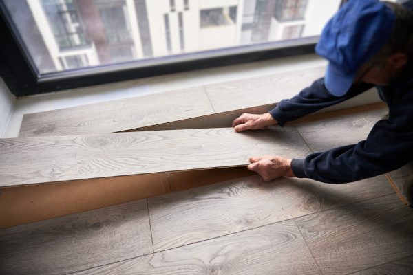 Man laying laminate flooring in apartment under renovation. Man laying laminate flooring in apartment under renovation.