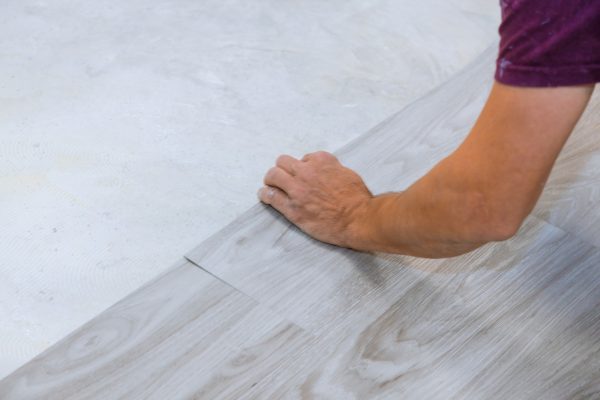 Work on laying worker installing new vinyl tile laminate wood texture floor. Work on laying worker installing new vinyl tile laminate wood texture floor.